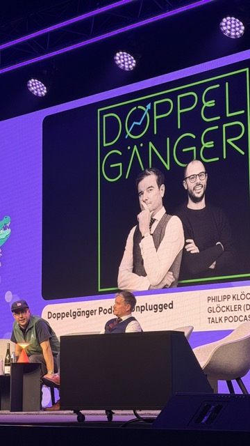 Doppelgänger Podcast Unplugged auf der OMR 2026 Bühne — Philipp Klöckner und Philipp Glöckler live, neongrünes Logo im Hintergrund